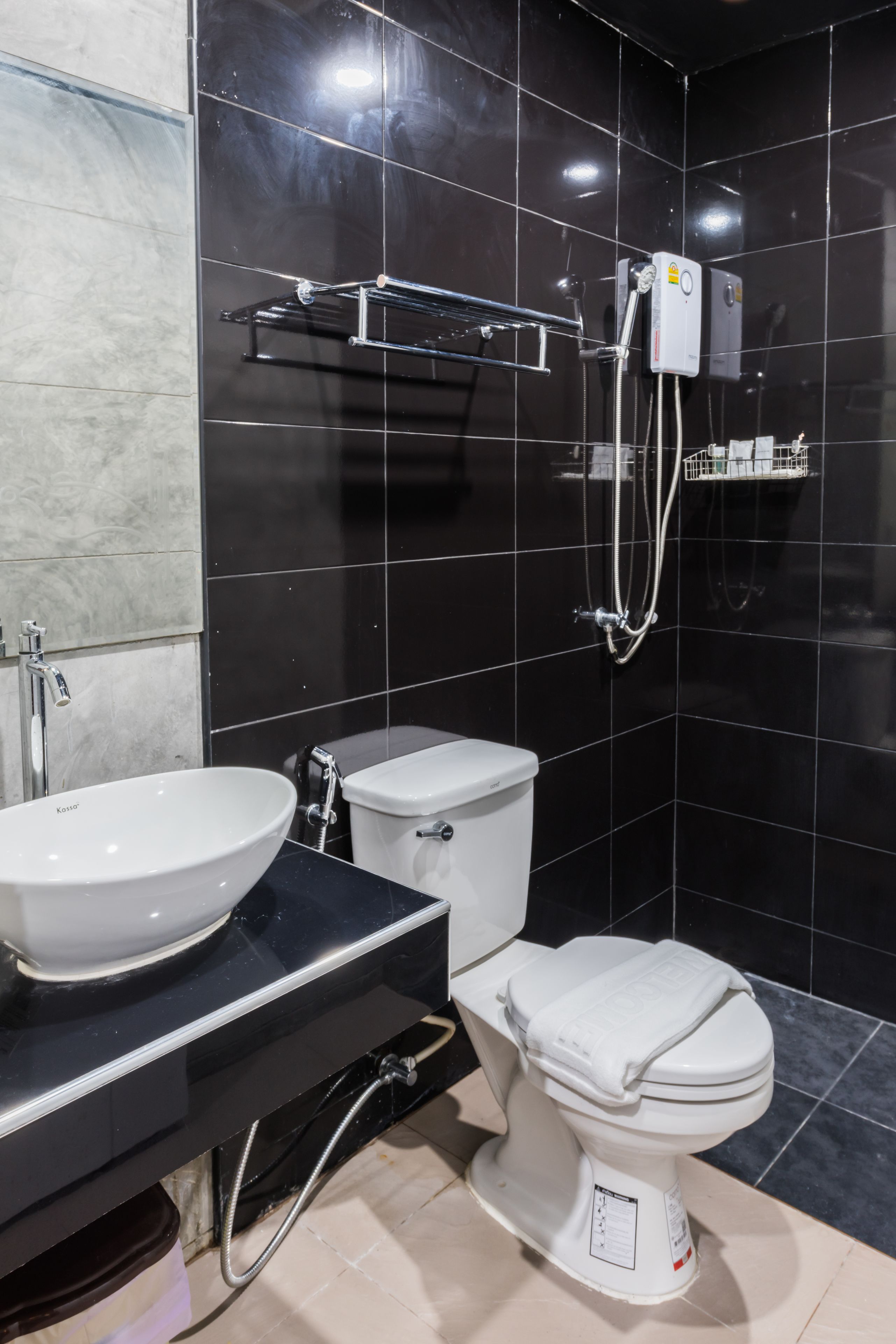 Um banheiro moderno com parede de azulejos pretos, pia branca e vaso sanitário.