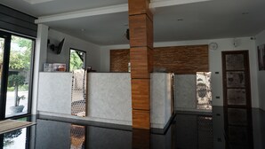 A modern kitchen with a central wooden column, a built-in refrigerator, and a window with a view of the outdoors. - Nine Blue Residence (Pattaya)