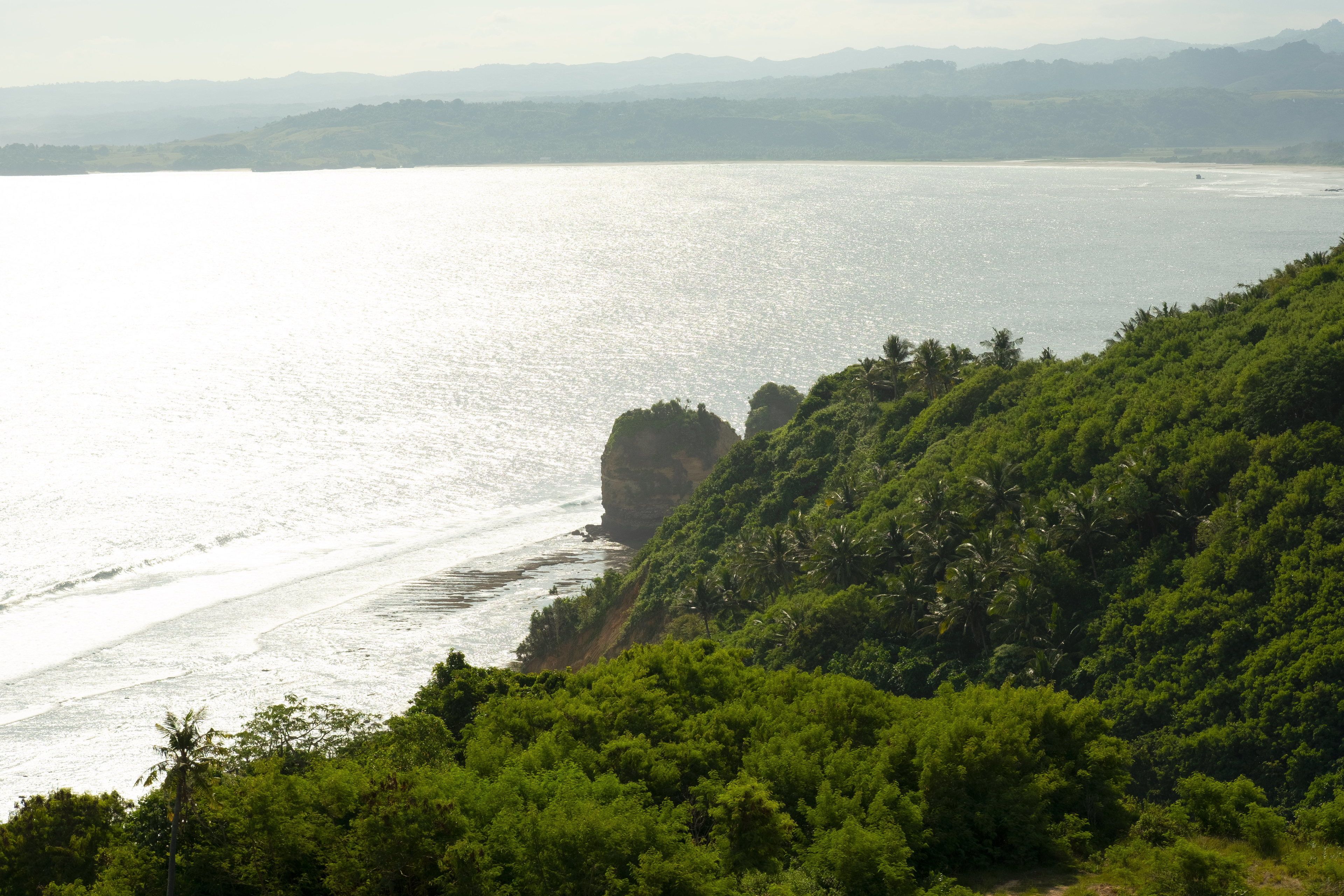 A coastal landscape with a clear view of the sea and a prominent rock formation.