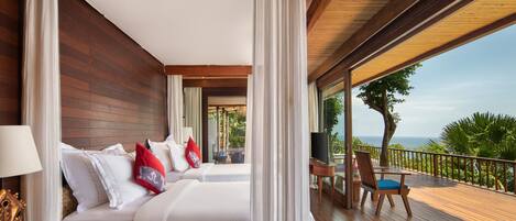 A hotel room with two beds, a balcony with a view of the ocean, and a wooden deck.