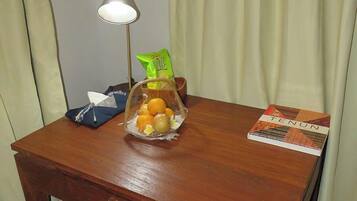 Un escritorio de madera con una lámpara, un frutero, una caja de pañuelos y un libro titulado 'TENUN'.