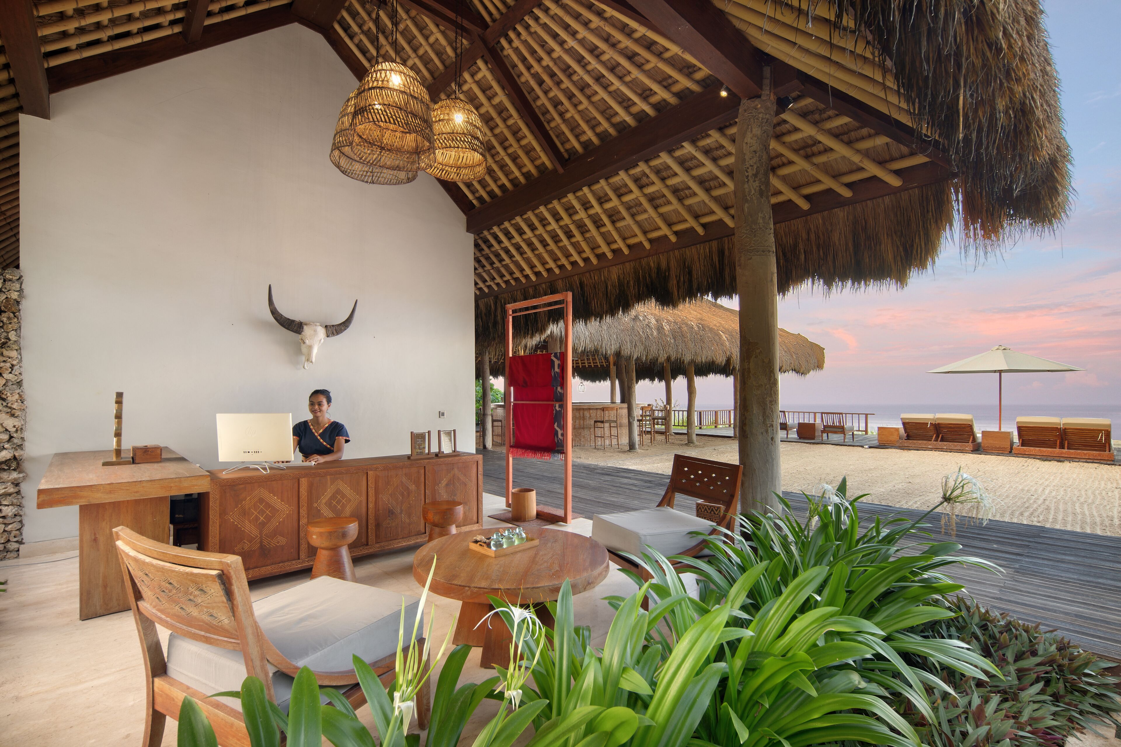 A beachside lounge with a wooden bar, seating, and a view of the beach.