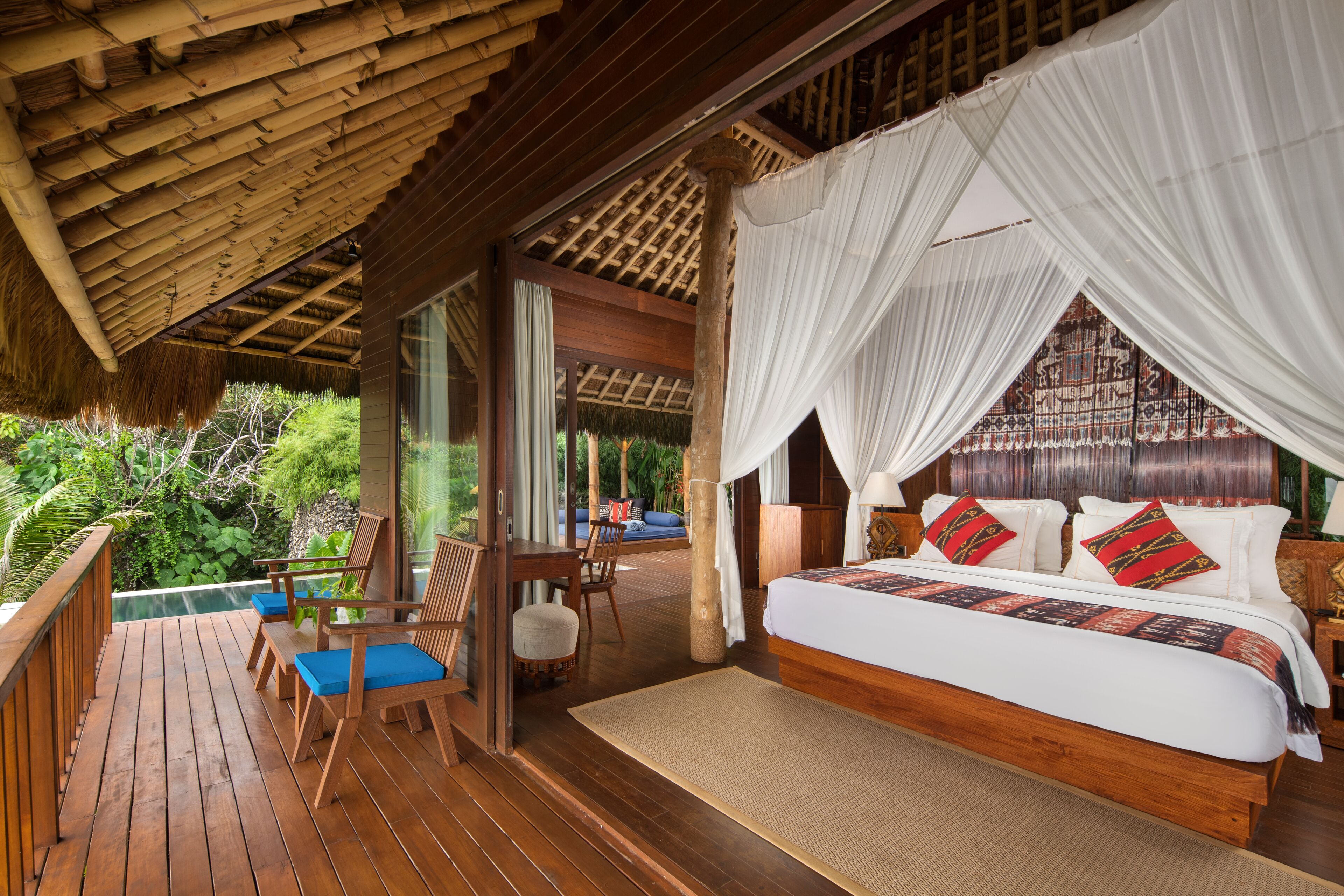 A wooden deck with a bed and a view of greenery.
