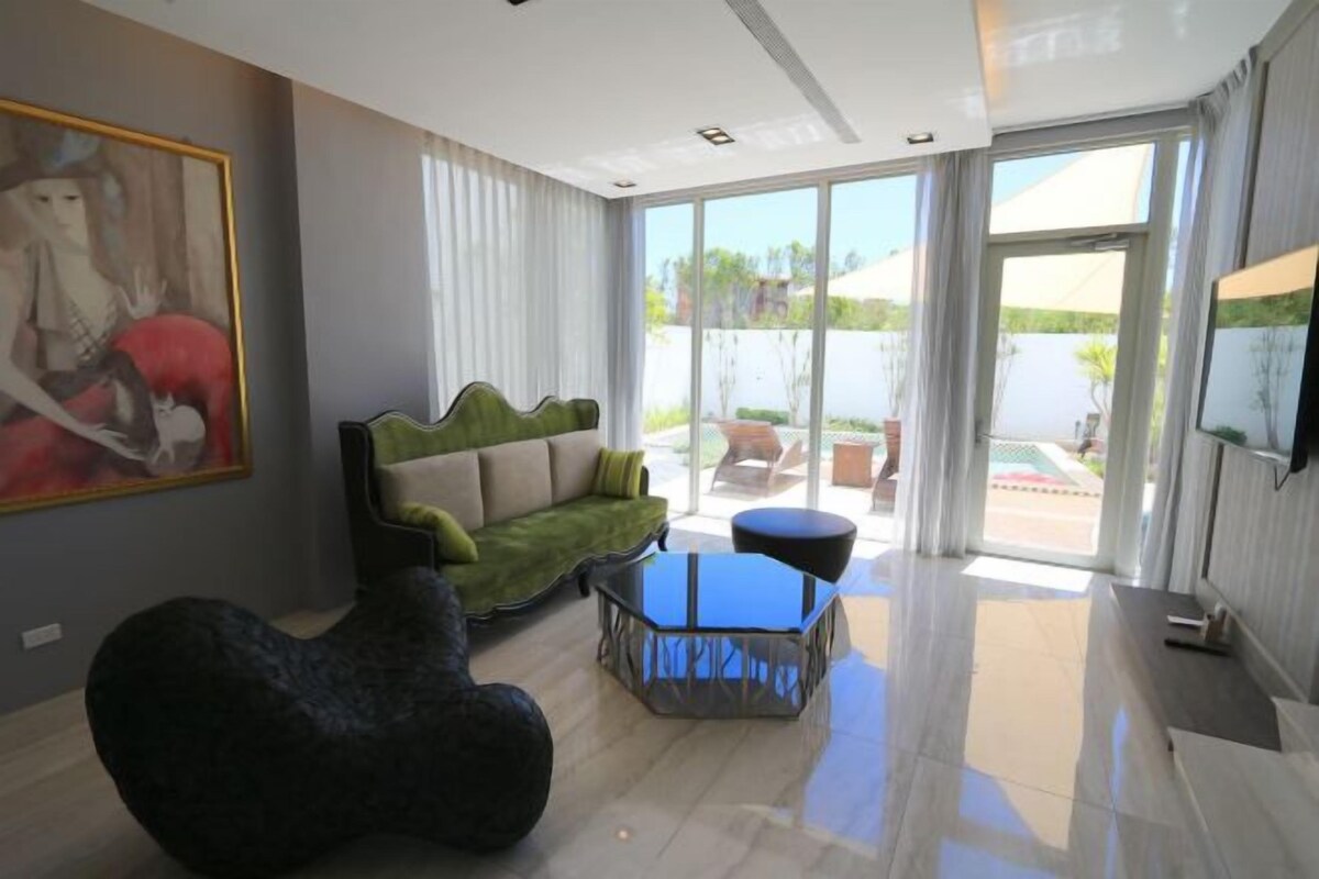A modern living room with a green sofa, a black bean bag, and a glass coffee table.