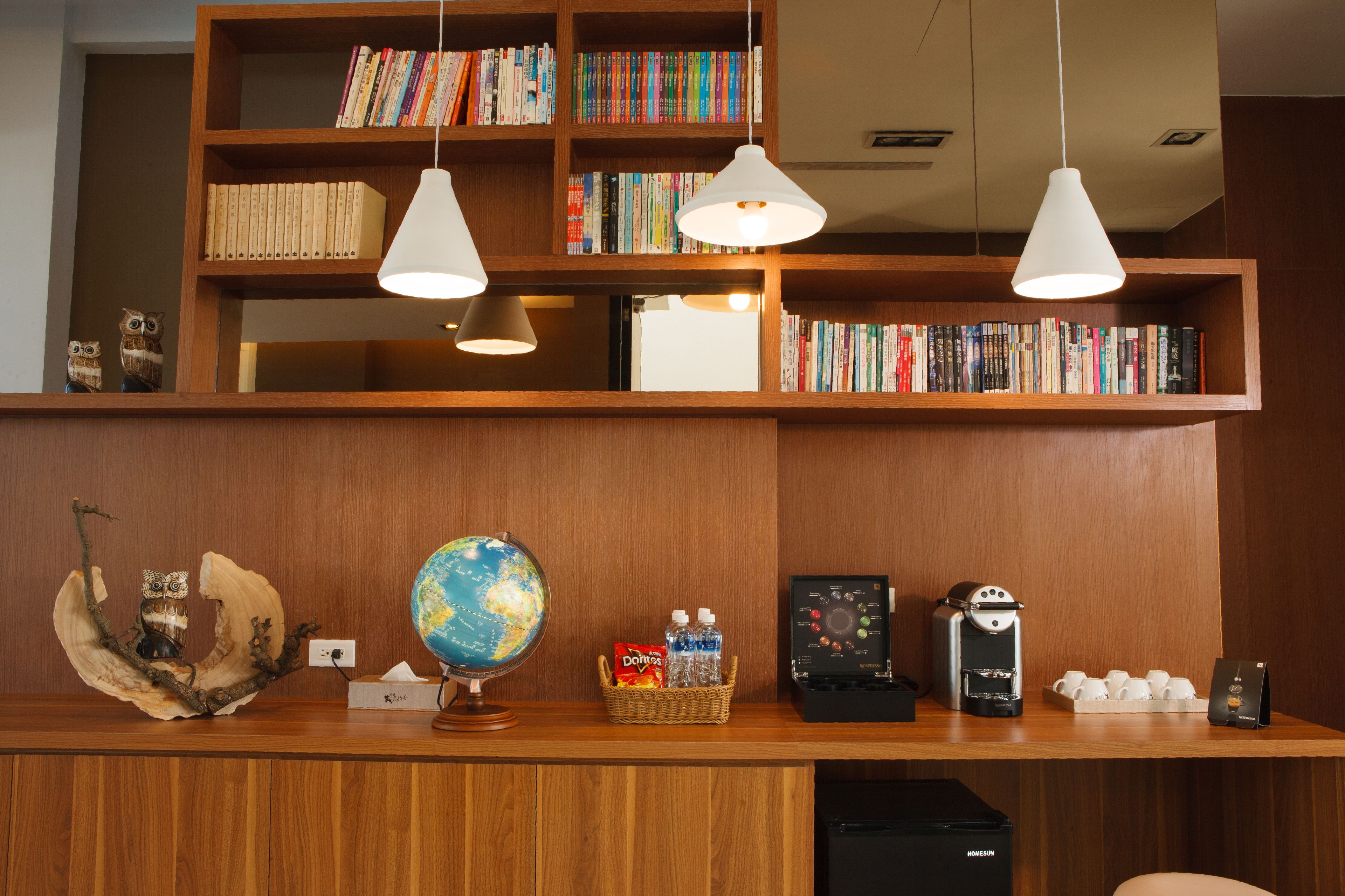 A reception desk with a globe, bookshelves, a coffee machine, and a basket of snacks.