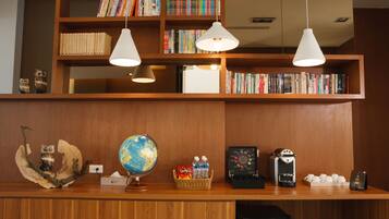 A reception desk with a globe, bookshelves, a coffee machine, and a basket of snacks.