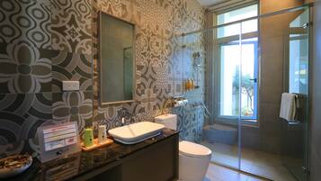 Un baño moderno con un papel tapiz estampado, un espejo grande, un lavamanos, un inodoro y un box de ducha de cristal.
