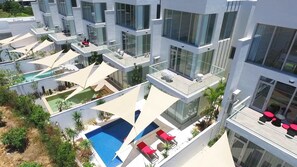 A modern hotel with multiple balconies, a central pool, and outdoor seating areas.