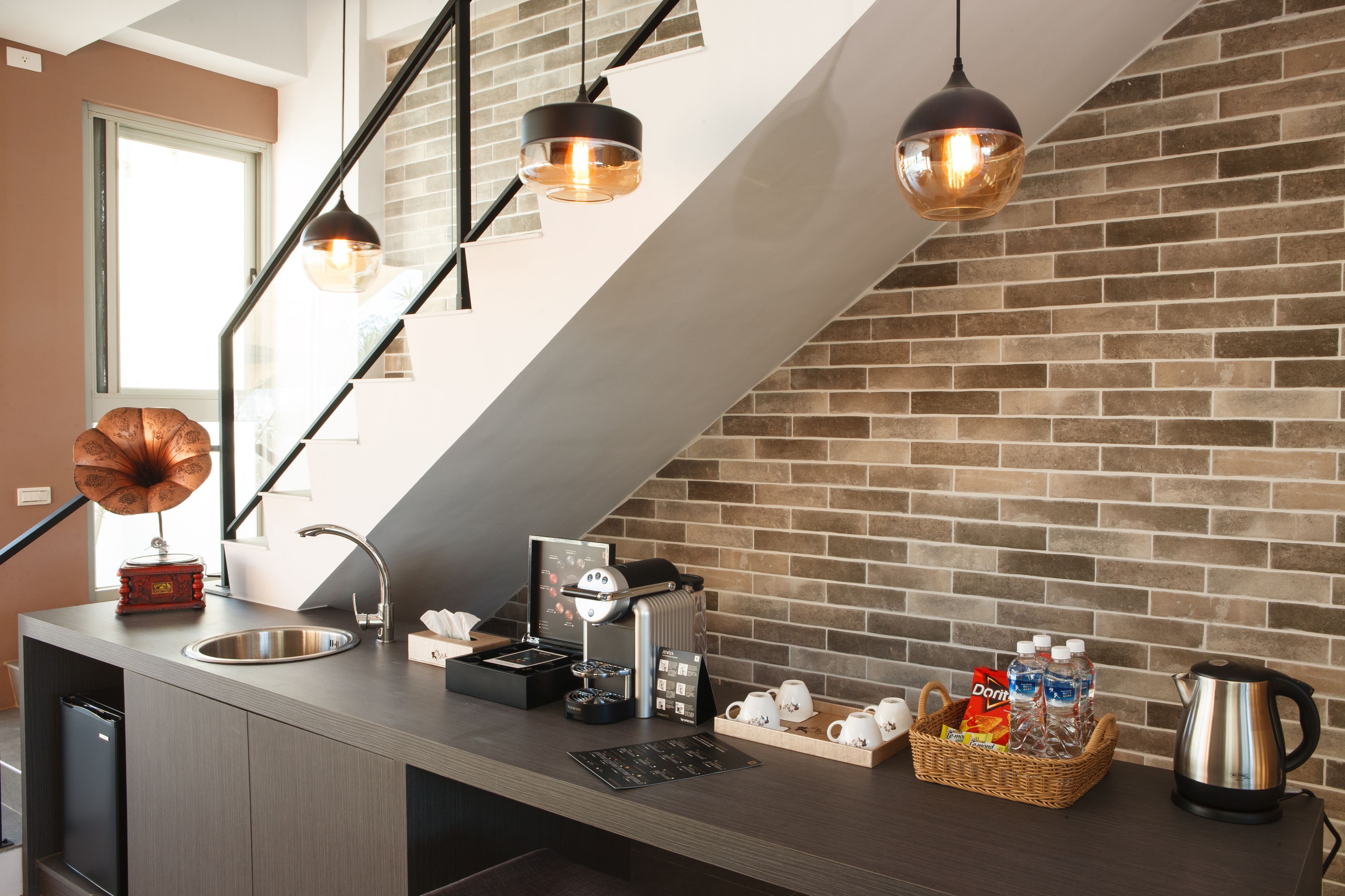Moderni keittiö, jossa on sisäänrakennettu espressokone, pesuallas ja kahvinvalmistusalue.