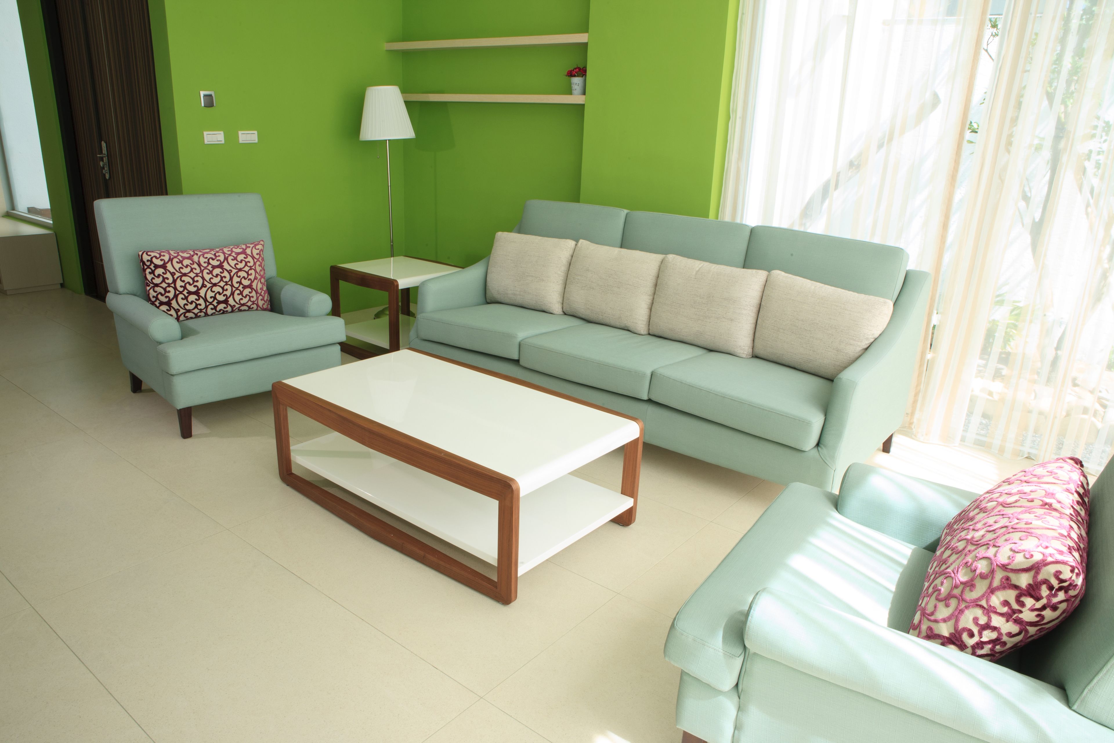 A living room with a light blue sofa, a matching armchair, a wooden coffee table, and a lamp.