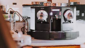 A coffee machine with multiple dispensers, a sink, and a countertop with a blurred object in the foreground.