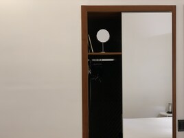 Et værelse med en seng, et lille bord med en lampe og et spejl på væggen.
