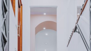 A staircase with marble steps leading to a room with a wooden door and a knife rack. - Albergo delle Regioni (Rome)
