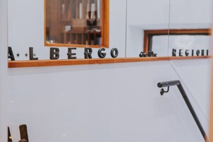 A mirror reflecting a room with the words "ALBERGO" and "REGIONI" on the wall.