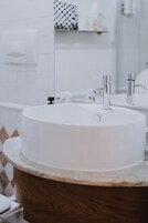 A bathroom with a white sink, wooden vanity, and a mirror.