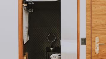 Ein Holzschrank mit Spiegel, ein kleiner schwarzer Hocker und ordentlich aufgerollte Handtücher.