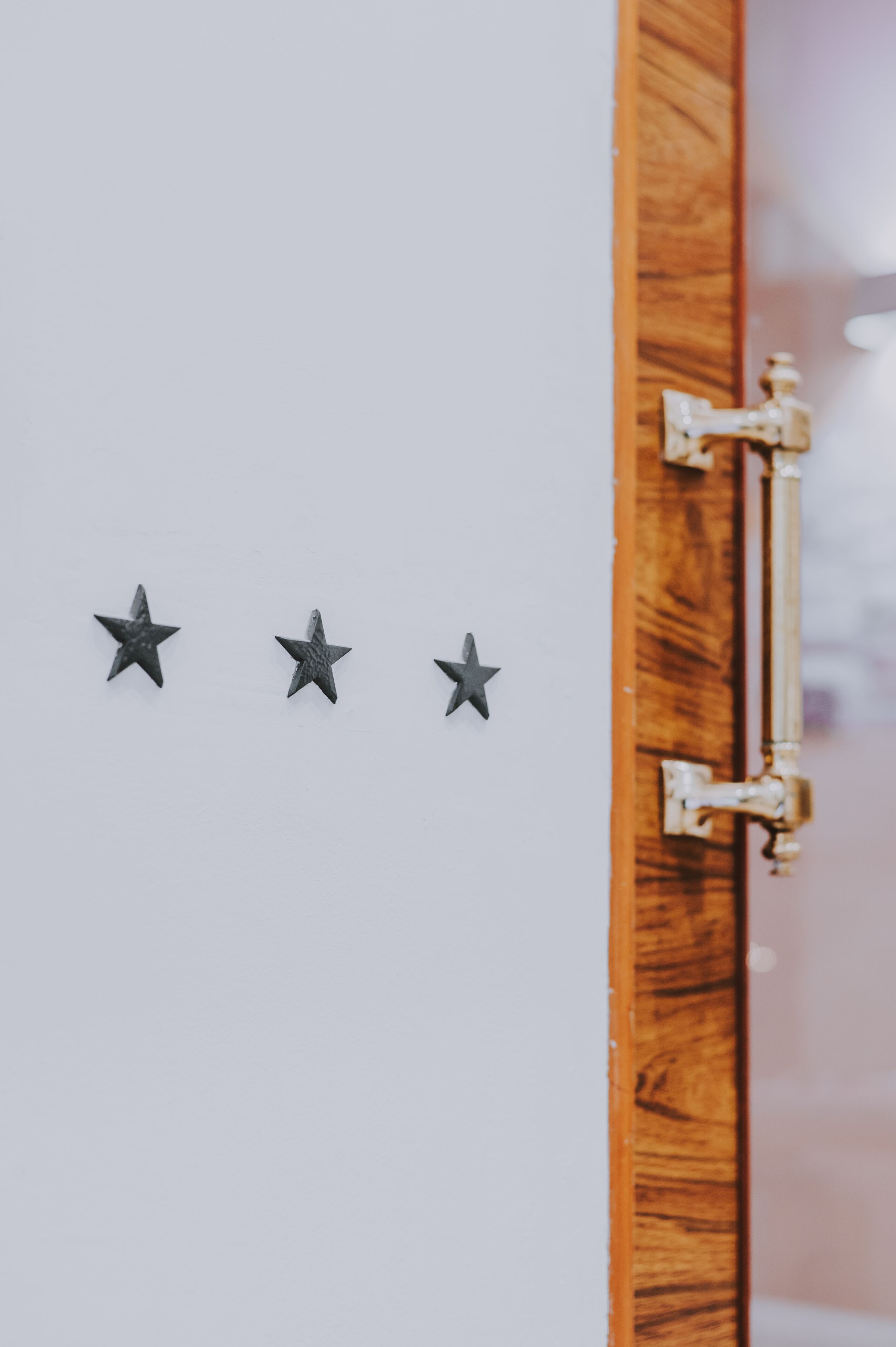 Una puerta de madera con un cierre metálico y tres adornos con forma de estrella sobre una pared blanca.