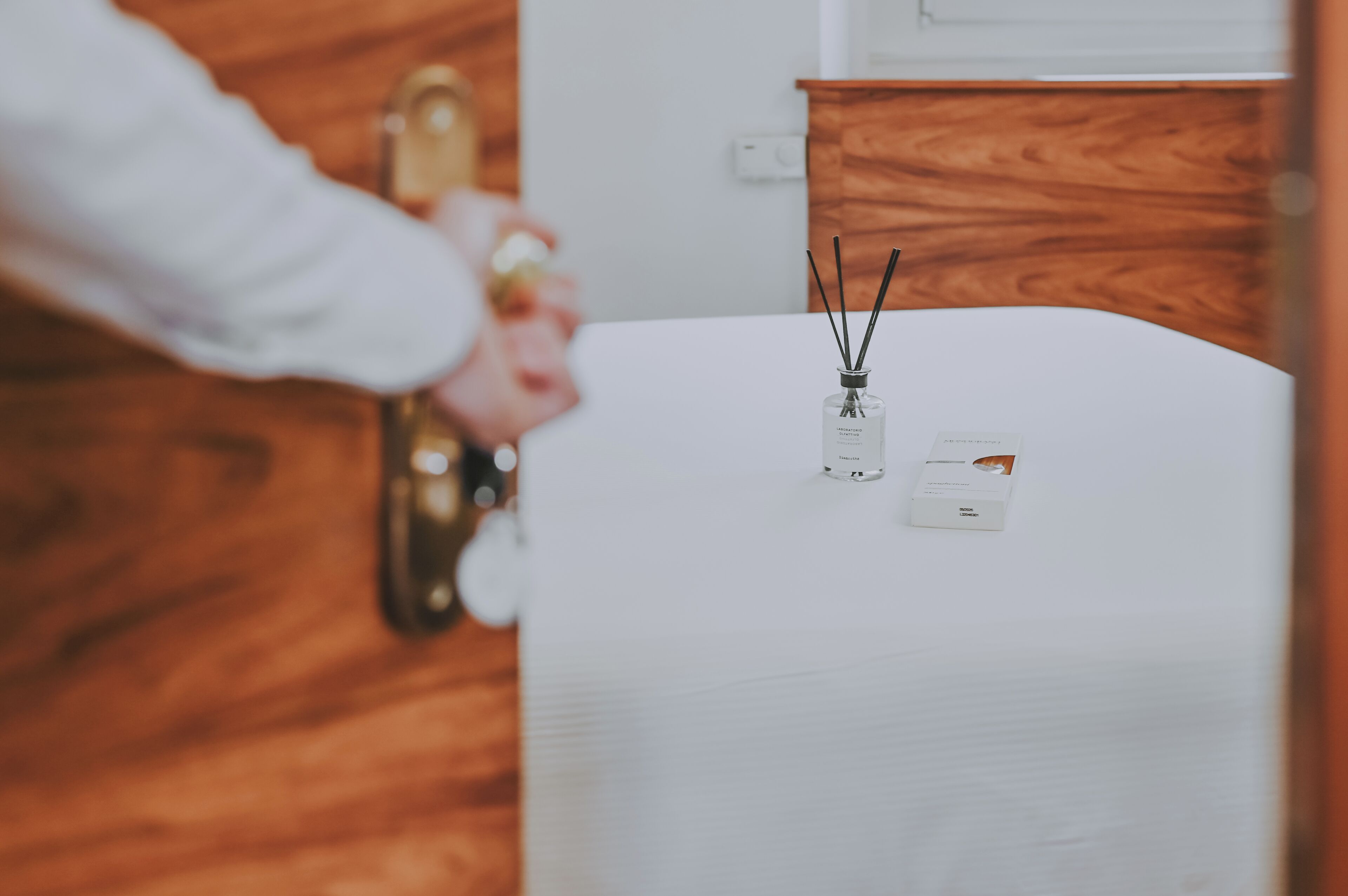 Una mesa blanca con dos botellas de vidrio de difusor de aroma y una tarjeta pequeña.