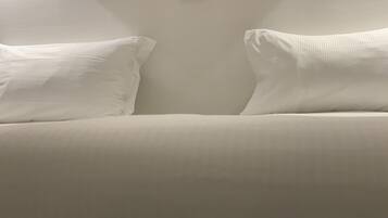 Una cama con dos almohadas y un pequeño objeto negro en la pared.