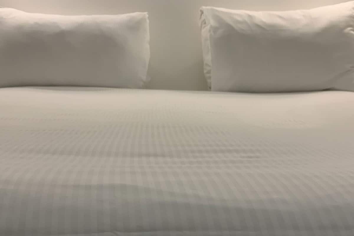 A bed with a white sheet and two pillows.