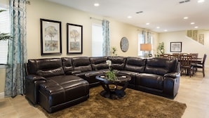 A living room with a sectional sofa, a coffee table with a plant, and a dining area with wooden furniture. - The Encore Club #4 - 10 Bed 10 Baths Villa (Kissimmee)