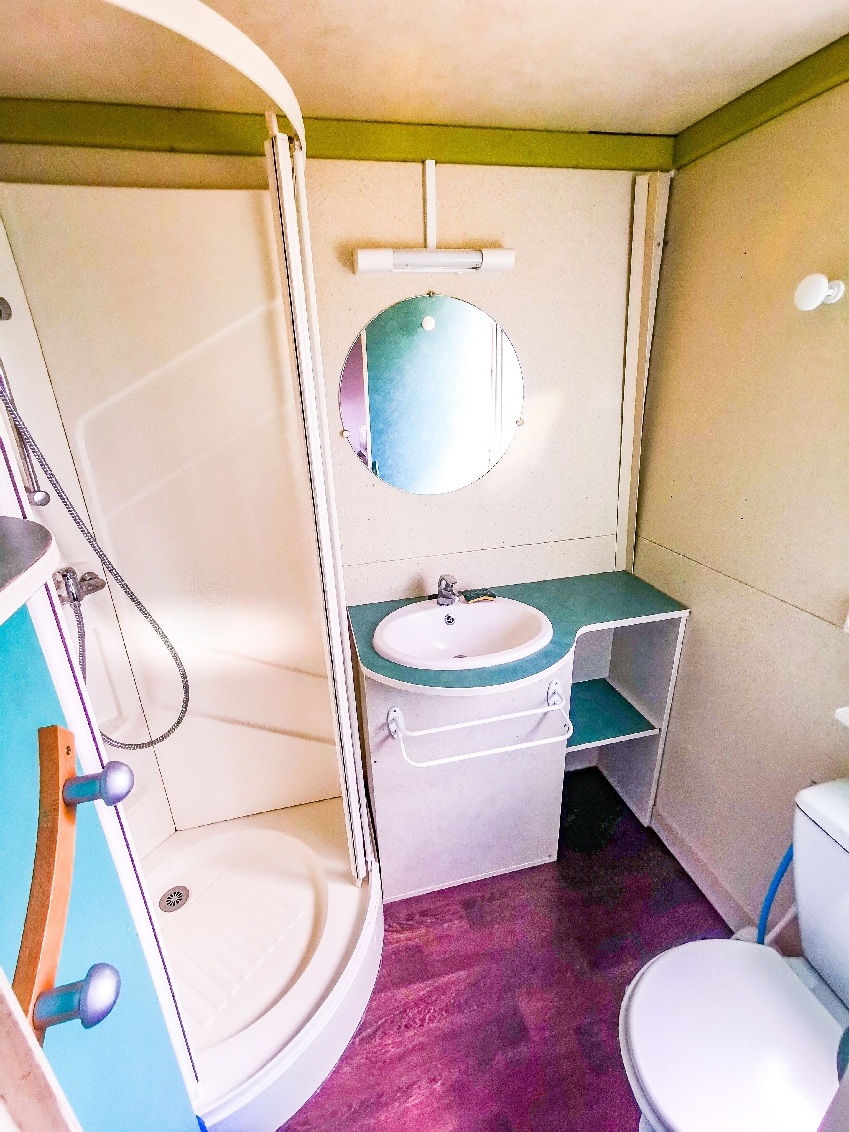 A compact bathroom with a shower, sink, and toilet.