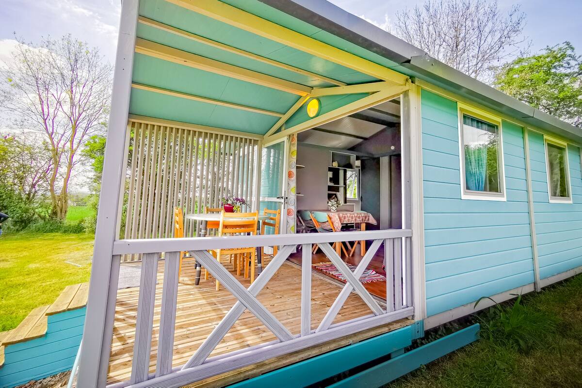 A mobile home with a porch, a dining table, and chairs.