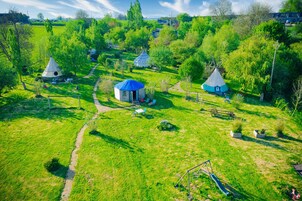 Zona rural con varias yurtas y una pequeña casa, rodeada de campos verdes y árboles.
