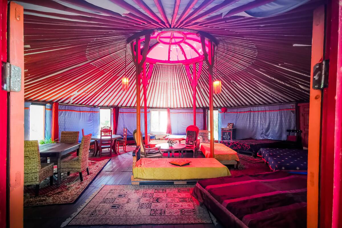 A traditional yurt with a central wooden structure, multiple seating areas, and a dining table.