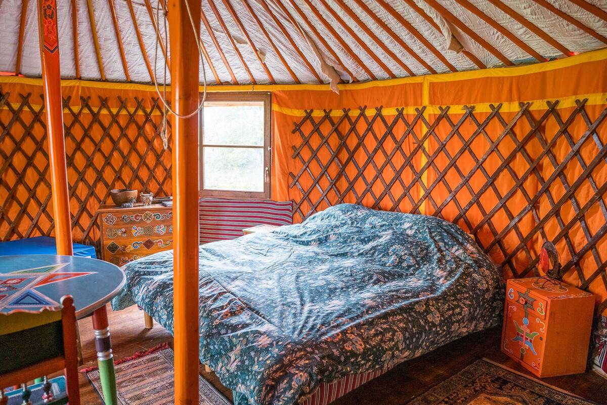 A traditional yurt with a bed, a small table, and a decorative box.