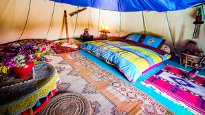 Ein Zelt mit einem Bett, Kissen, einer Lampe und verschiedenen Dekorationselementen.