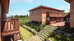 A two-story building with a brick facade, a wooden deck, and a stone staircase leading to a covered area.