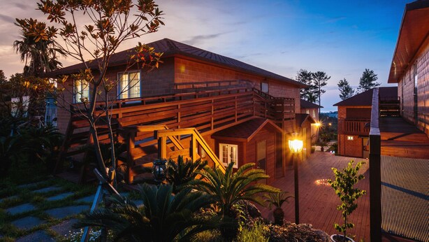 A modern house with a wooden staircase, a balcony, and a well-lit outdoor area.