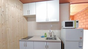 A compact kitchen with white cabinets, a sink, a microwave, and a refrigerator.