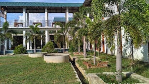A multi-story building with a green roof, surrounded by greenery and a small water feature. - Hotel Bundala Park - Hostel (Lunugamvehera)