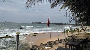 A beach with a flag, rocks, and a bench. - Hotel Bundala Park - Hostel (Lunugamvehera)