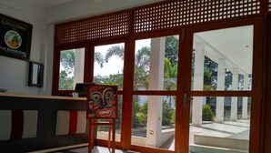 A reception area with a wooden partition, a reception desk, and a painting of a face. - Hotel Bundala Park - Hostel (Lunugamvehera)
