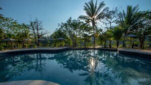 A clear swimming pool surrounded by palm trees and shaded seating areas. - Le Bel Air Resort Luang Prabang (Luang Prabang)