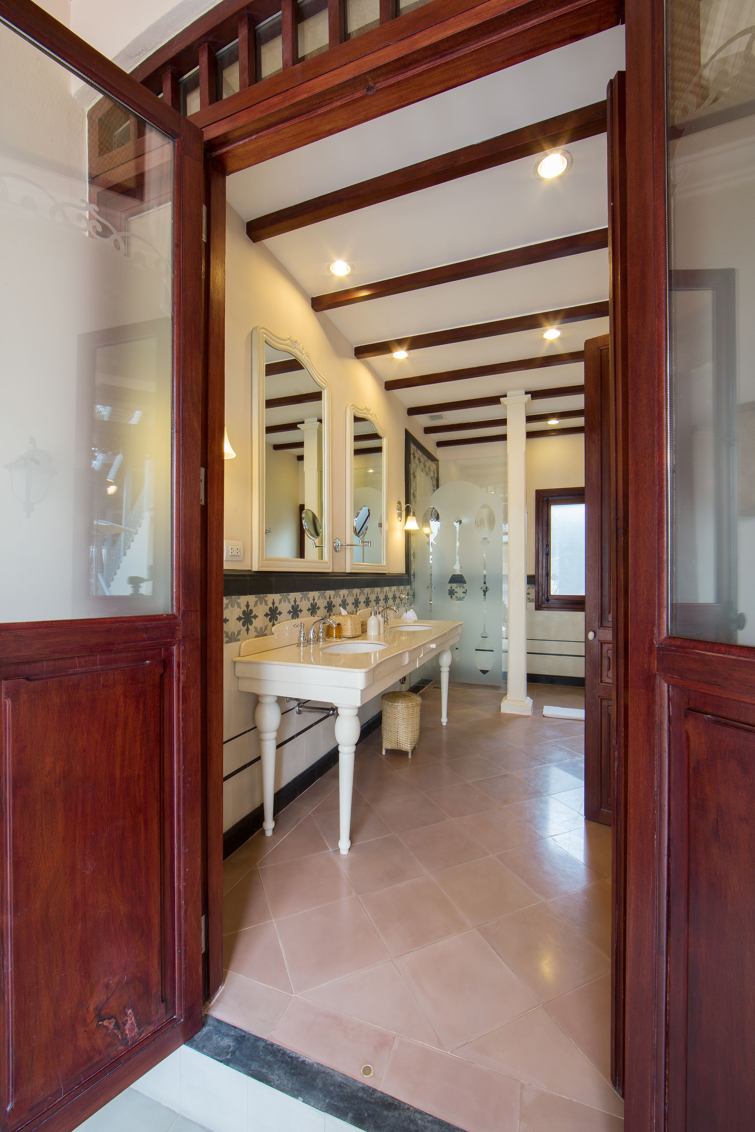 Un baño espacioso con un tocador amplio, un espejo e piso de baldosas.