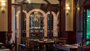 A dining area with a brick wine cellar, wooden furniture, and wall-mounted light fixtures. - Le Bel Air Resort Luang Prabang (Luang Prabang)