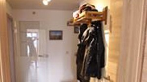A narrow hallway with wooden flooring, a bench, and a coat rack with hanging items. - Ferienhaus Thimlefi (Reit im Winkl)