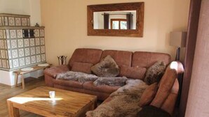 A living room with a brown sofa, a wooden coffee table, and a cabinet with patterned doors. - Ferienhaus Thimlefi (Reit im Winkl)
