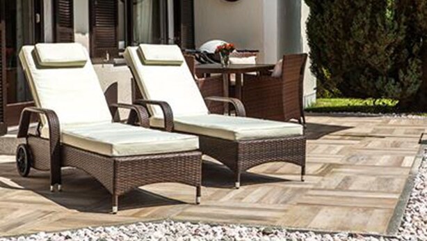 Eine Terrasse mit zwei Korbsessel-Lounges und einem Tisch mit Stühlen.