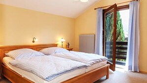 Ein Doppelbett mit Holzbettgestell in einem Zimmer mit Blick auf einen Balkon.