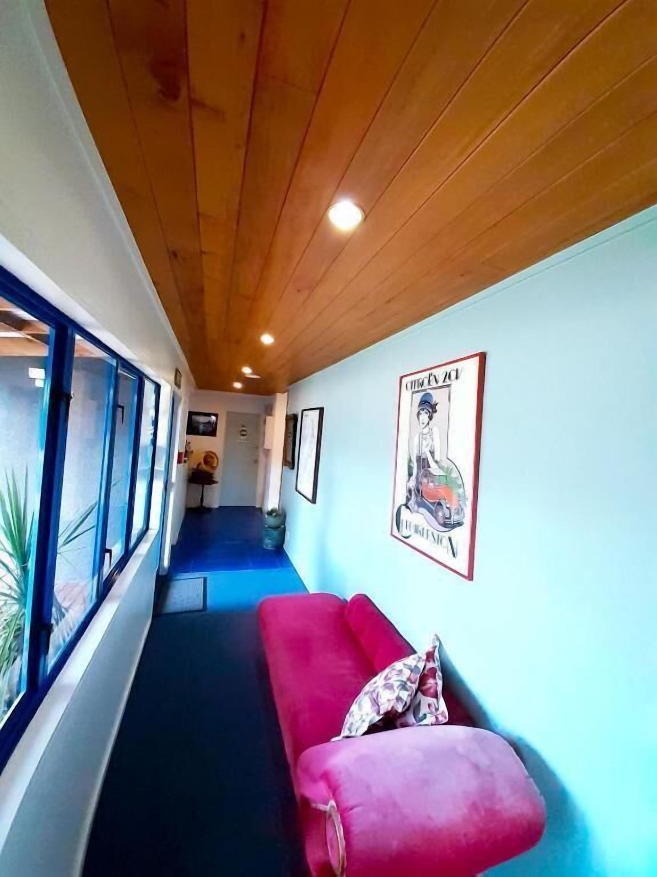 A corridor with a wooden ceiling, a red sofa, and a poster on the wall.