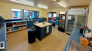 A kitchen with a central island, a refrigerator, and a sink. - Tongariro River Retreat - Hostel (Turangi)