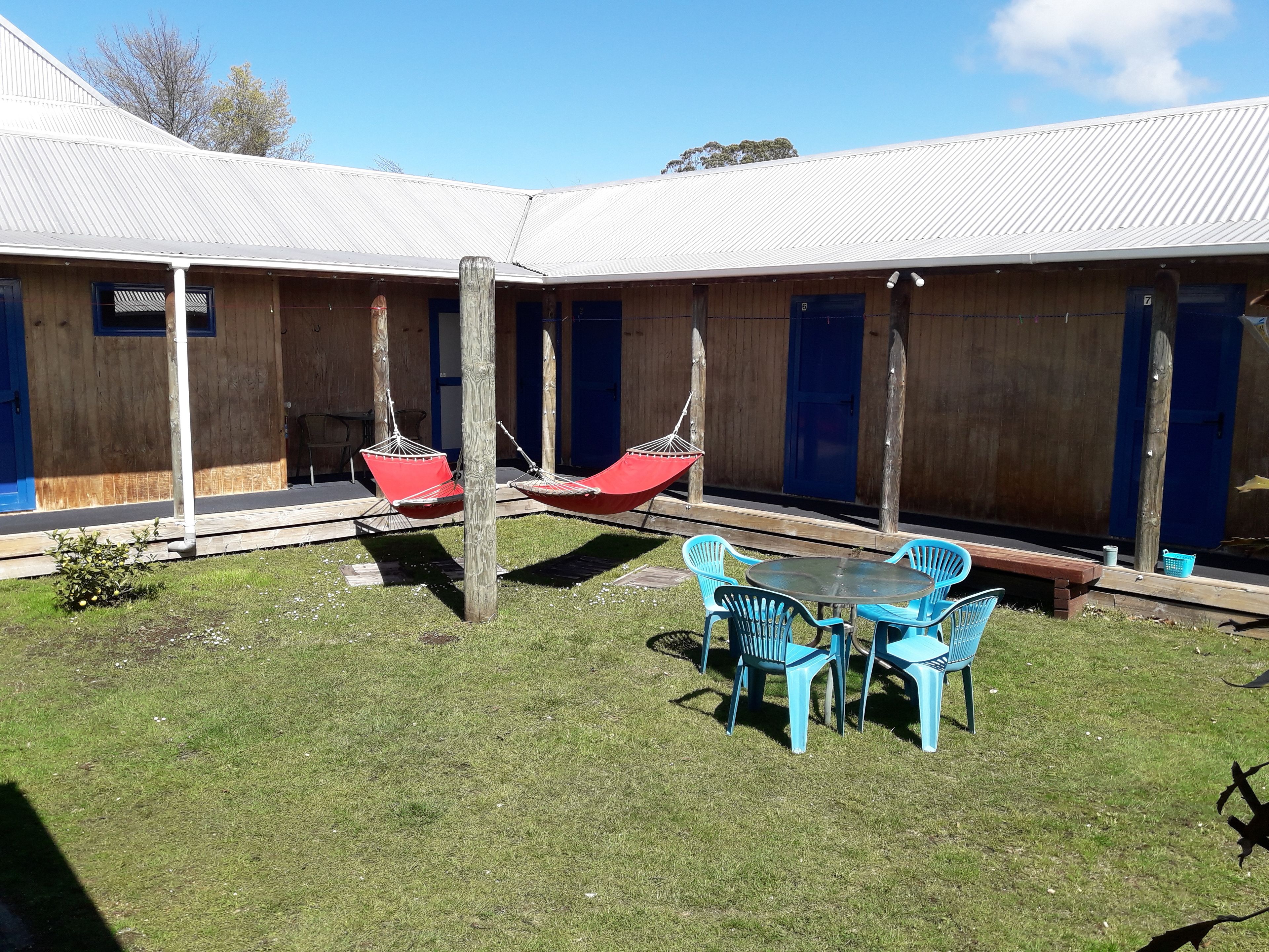 A courtyard with a wooden fence, a swing set, and a table with chairs.