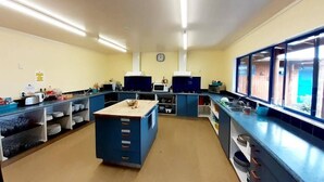 A kitchen with blue cabinets, a central island, and a clock on the wall. - Tongariro River Retreat - Hostel (Turangi)