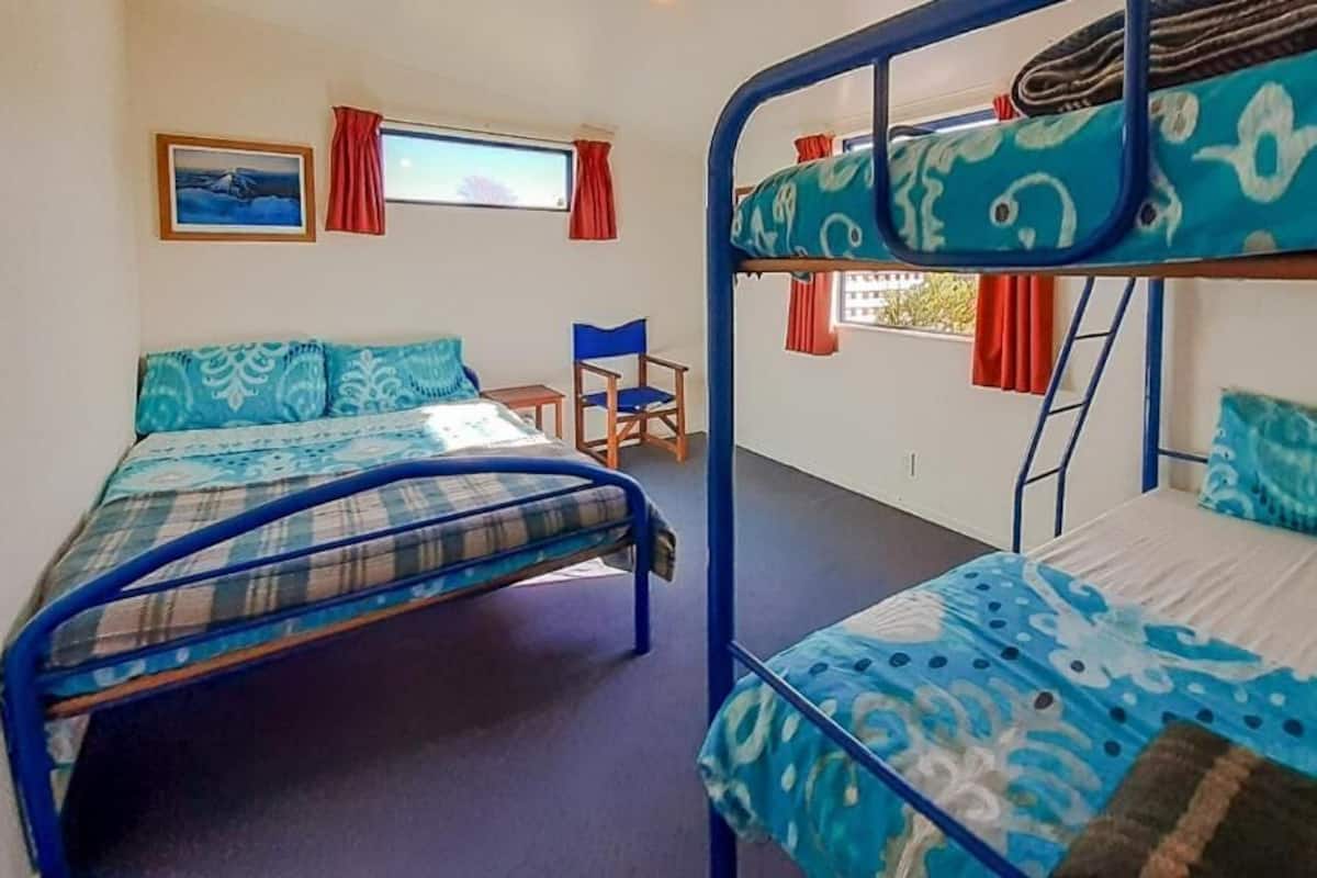 A room with bunk beds, a desk, and a chair.