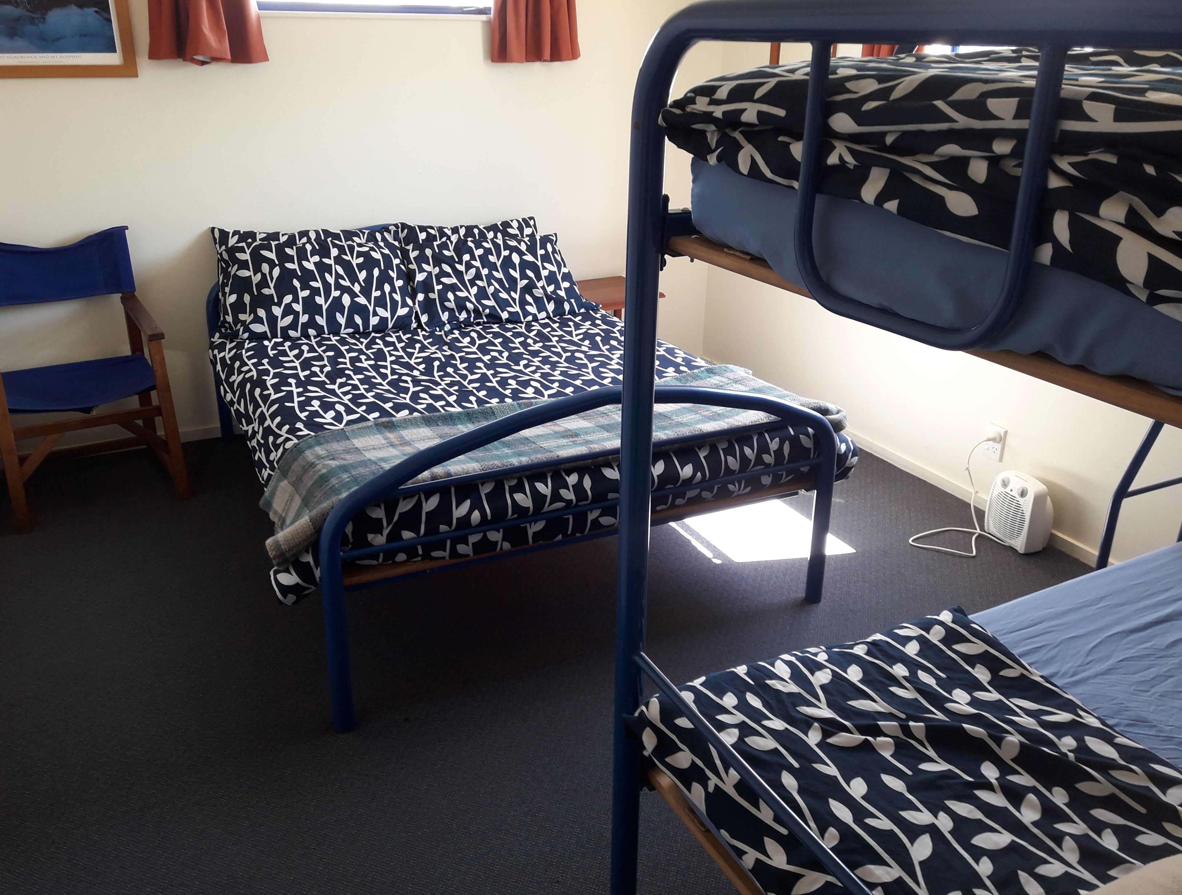 A dormitory room with bunk beds, a chair, and a small table.